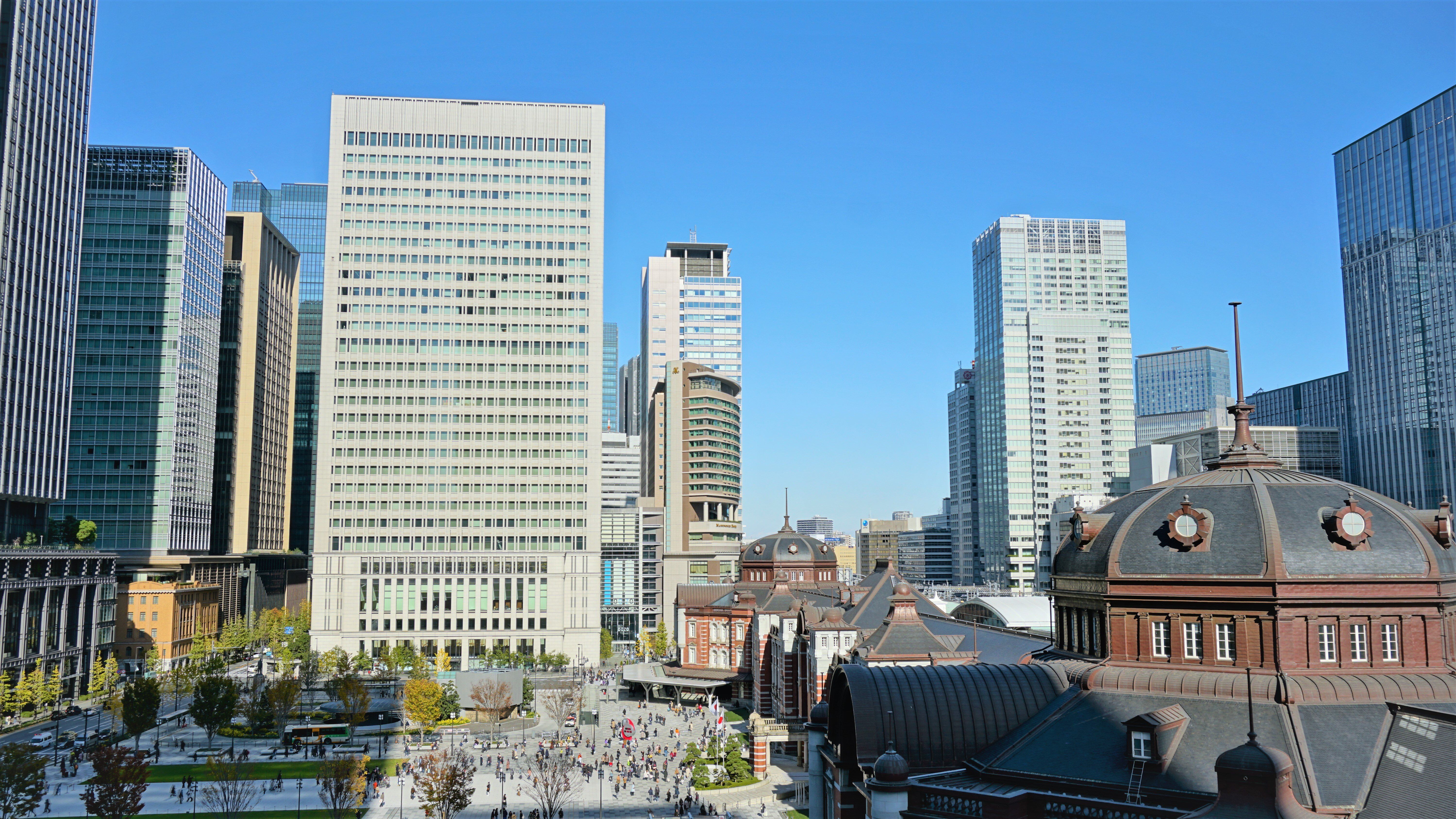 People crossing the plaza in front of Tokyo Station, between the office towers of Marunouchi